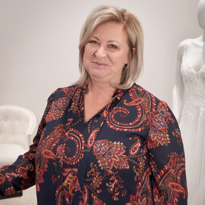 Women Owned Business Blog Header Of Maggie Sottero CEO Kelly Midgley In Front Of Maggie Sottero Wedding Dresses