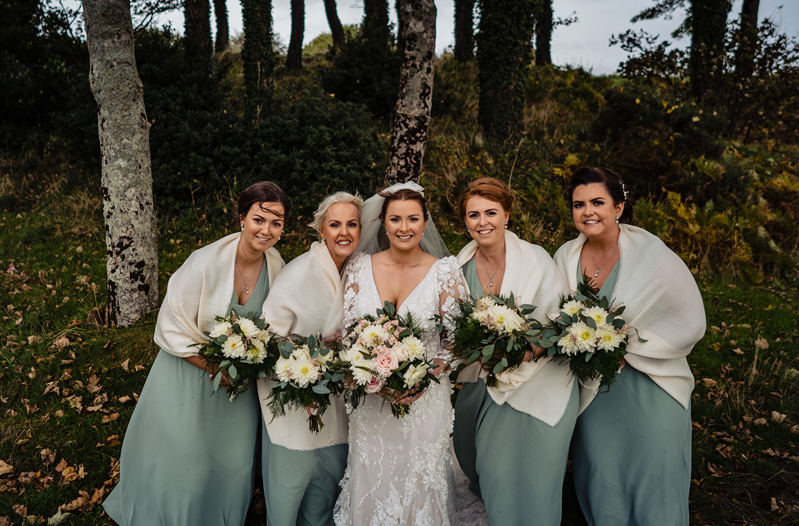 Photo de la mariée vêtue d'une robe de mariée appelée Cruz par Sottero et Midgley avec des demoiselles d'honneur vêtues de vert menthe avec des enveloppes de fourrure