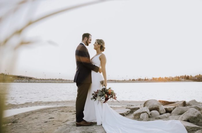 Bride Wearing V-Neck Wedding Dress Called Fernanda By Maggie Sottero Standign With Groom By Beautiful River