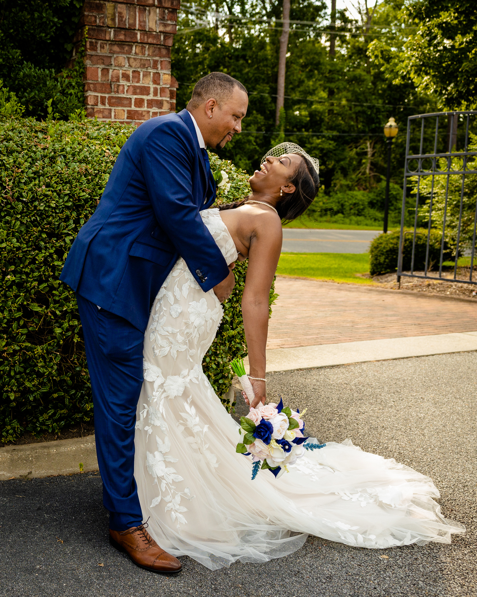 Mariée portant une robe de mariée de printemps avec le marié en costume bleu marine tenant un bouquet portant une robe appelée Hattie par Rebecca Ingram