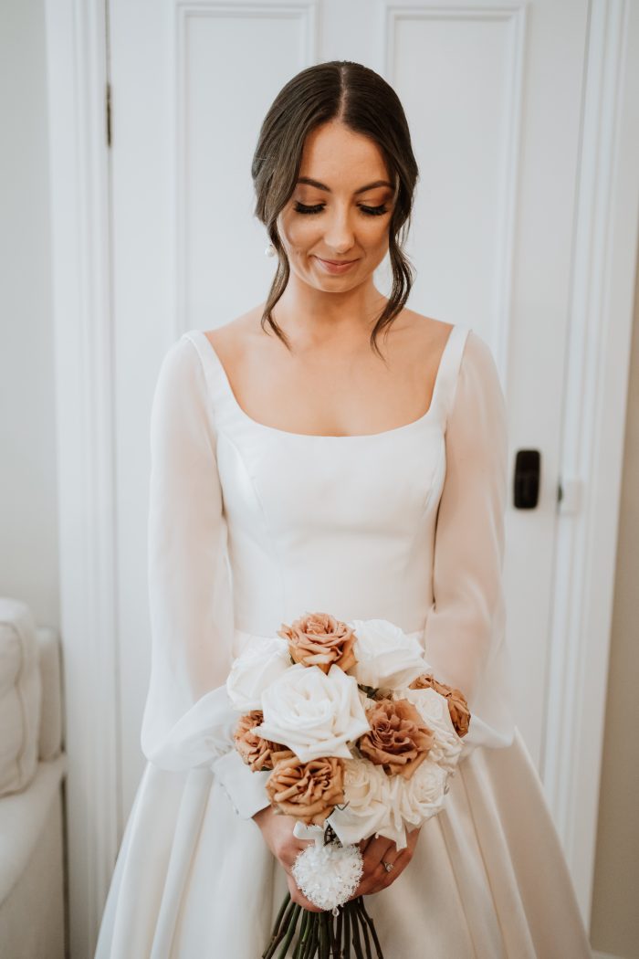 Bride Wearing Square Neckline Wedding Dress Called Selena By Maggie Sottero With Ivory And Rust Colored Bouquet 