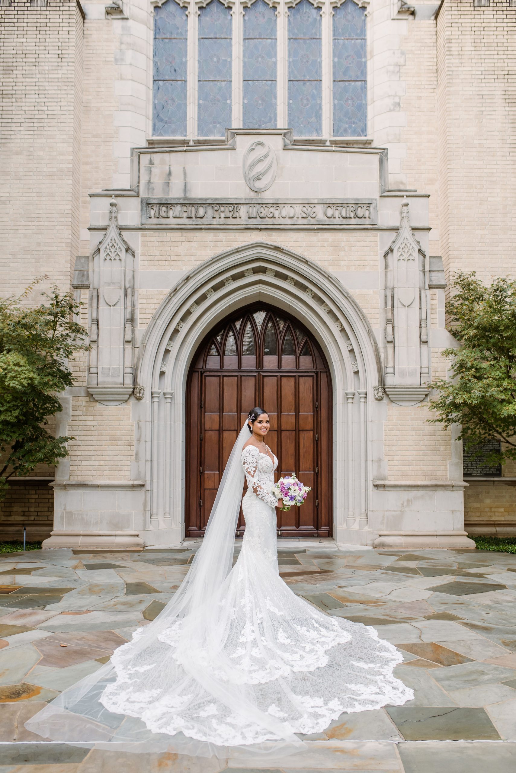 Mariée portant une robe de mariée appelée Sacramento Toscane Royale par Maggie Sottero debout devant l'église