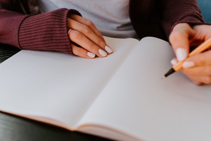 Woman With White Nail Polish Writing In Journal