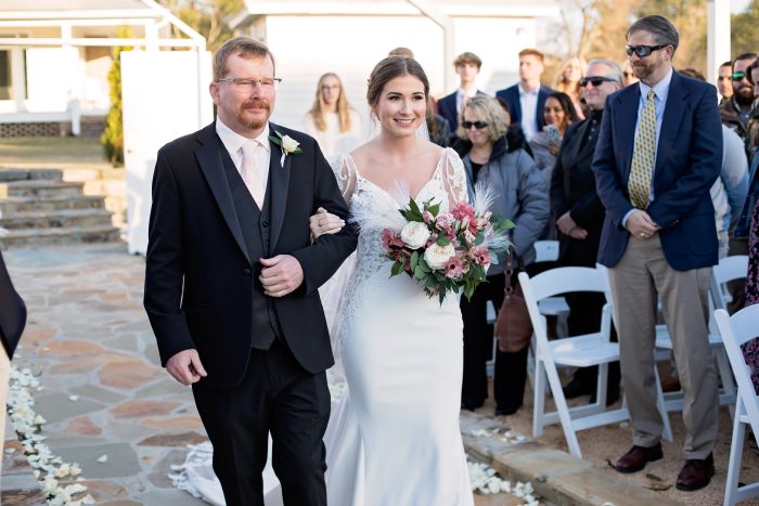 Bride Walking Down The Aisle With Father Of The Bride Wearing A Crepe Wedding Dress Called Nikki By Maggie Sottero