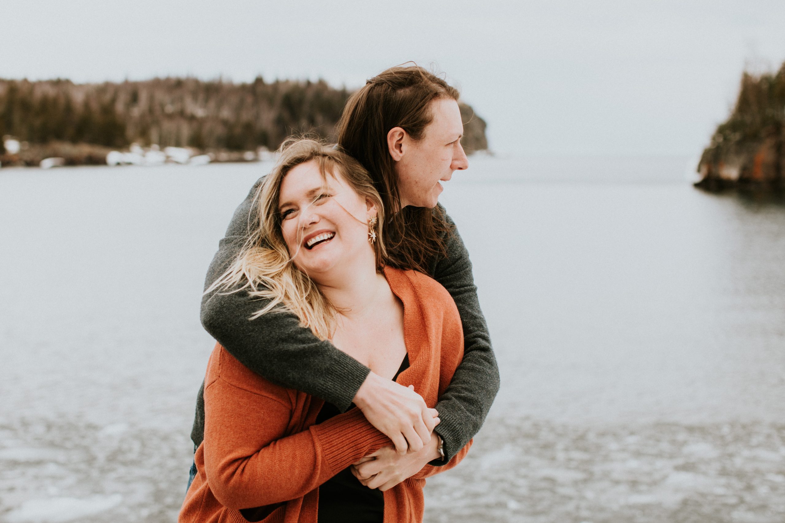Mariée en orange avec fiancé devant le lac pendant la séance photo de fiançailles