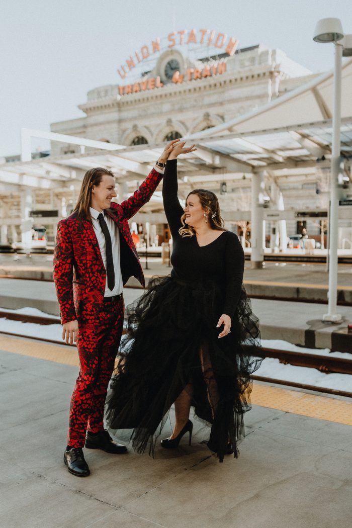 Bride In Black Dress With Fiance In Red Suit During Engagement Photoshoot In Denver Union Station