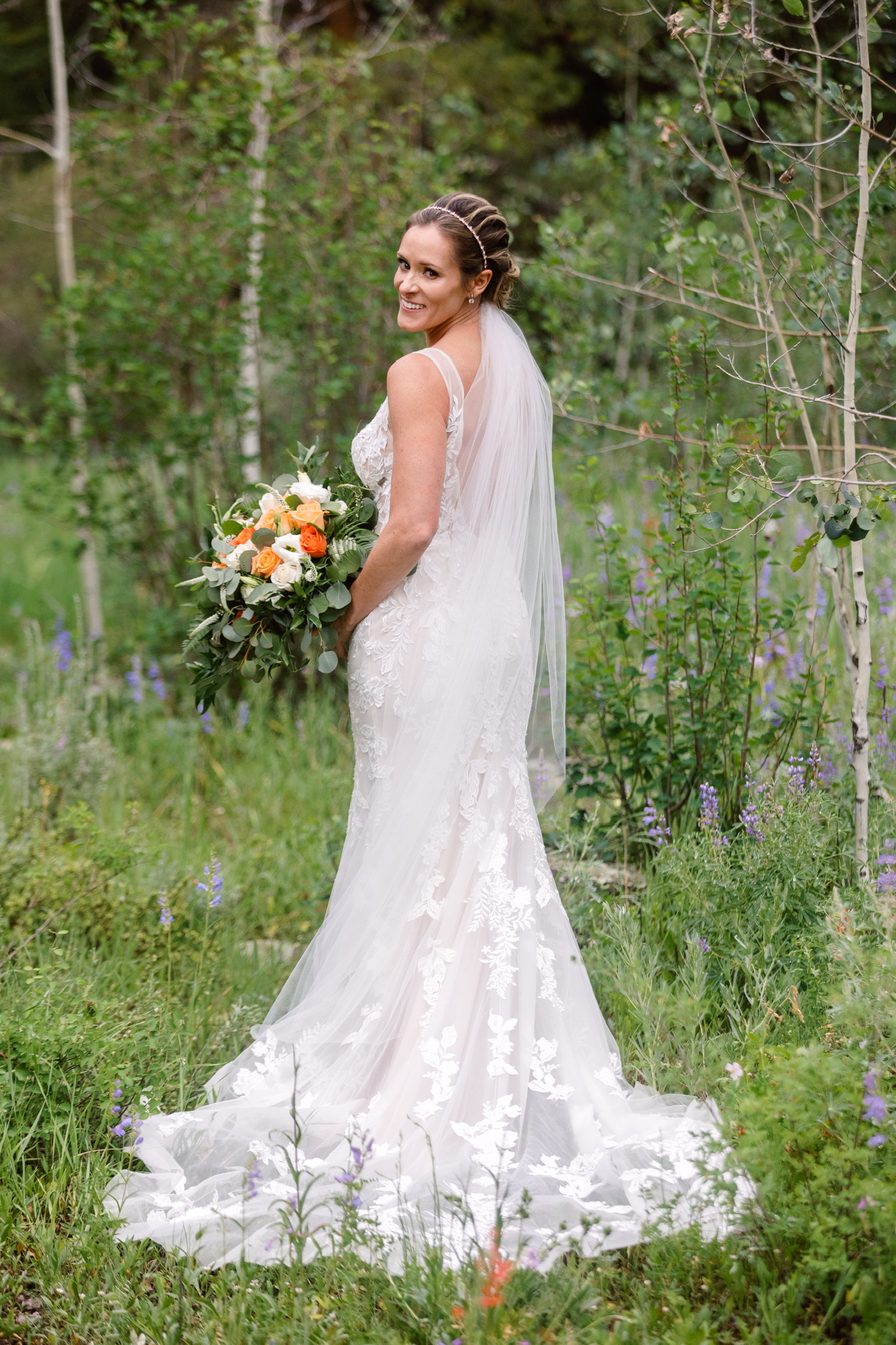 La mariée porte une robe de mariée ajustée et évasée en dentelle appelée Greenely par Maggie Sotter