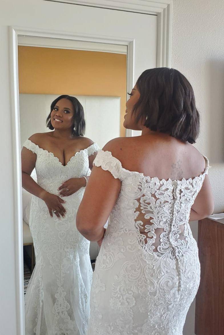 Mariée debout devant un miroir vêtue d'une robe de mariée appelée Kennedy par Maggie Sottero