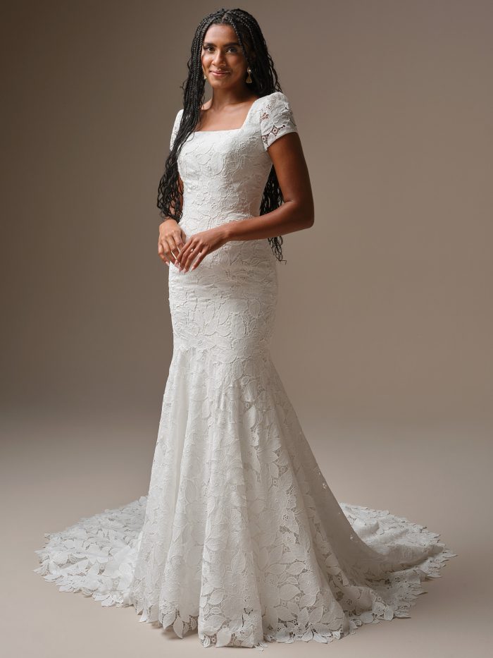 Bride wearing the Dakota Leigh sheath wedding dress by Maggie Sottero, featuring a square neckline, short sleeves, and bold floral lace with a fitted silhouette and sweeping train.