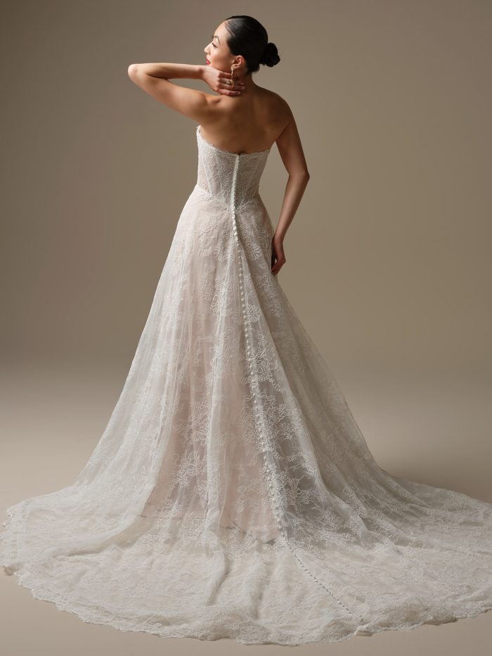 Back view of the Granger wedding dress, a strapless lace A-line gown with covered buttons and a chapel-length lace train, showing floral lace details and a soft flowing silhouette.