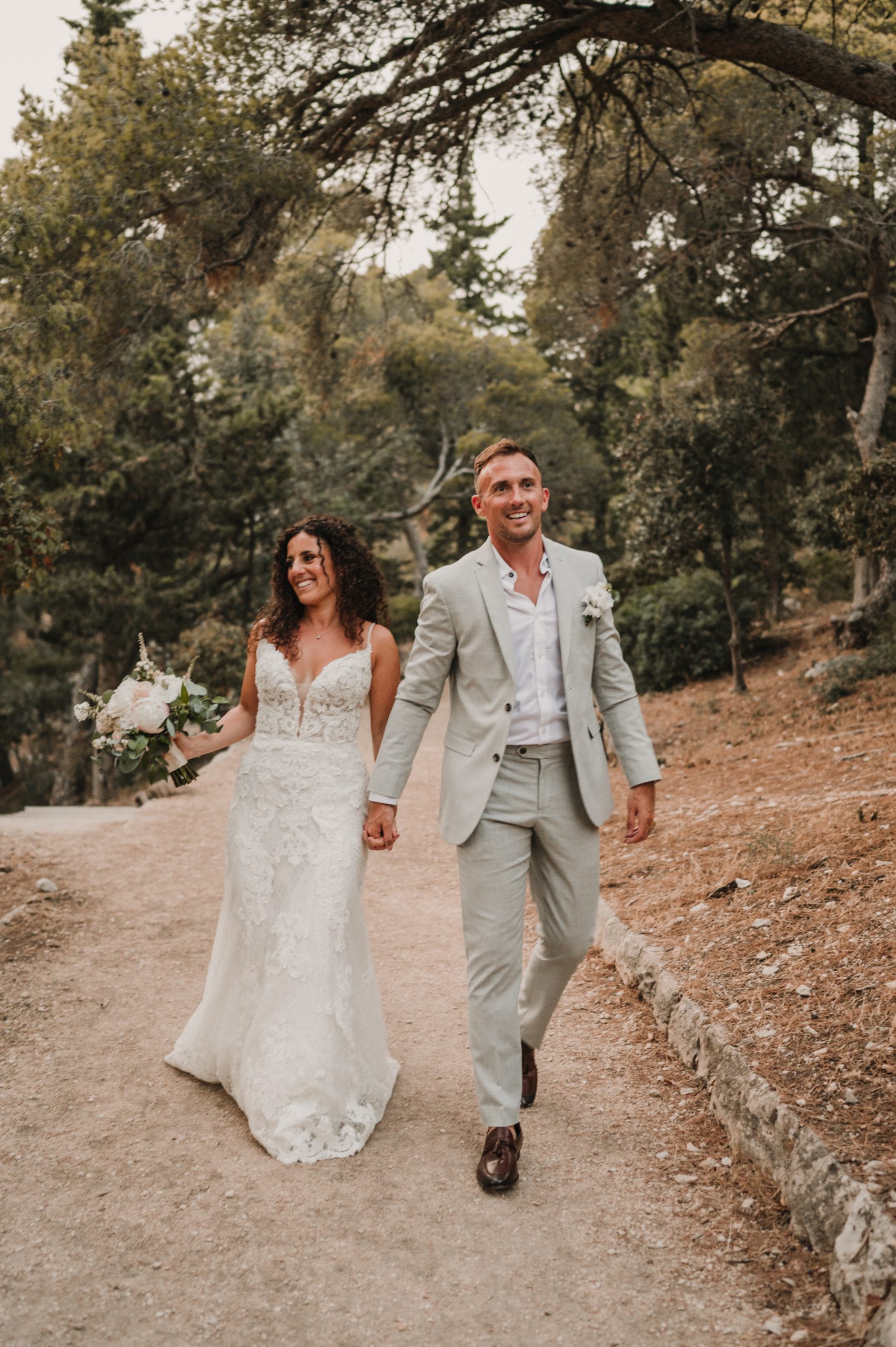 Mariée marchant avec le marié vêtue d'une robe de mariée sexy appelée Tuscany Lane par Maggie Sottero