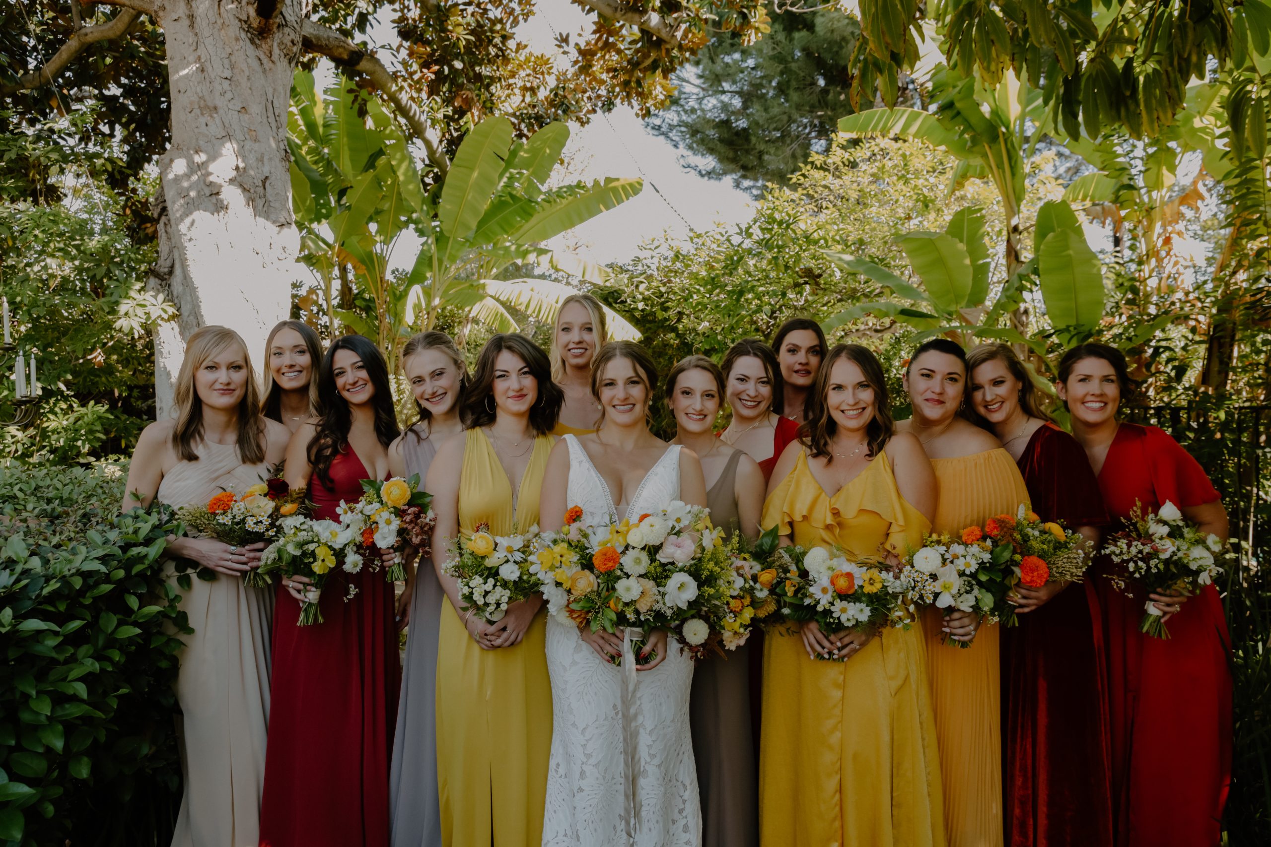 Mariée portant une robe de mariée d'été appelée Burke par Maggie Sottero avec des demoiselles d'honneur en jaune et vert avec des fleurs