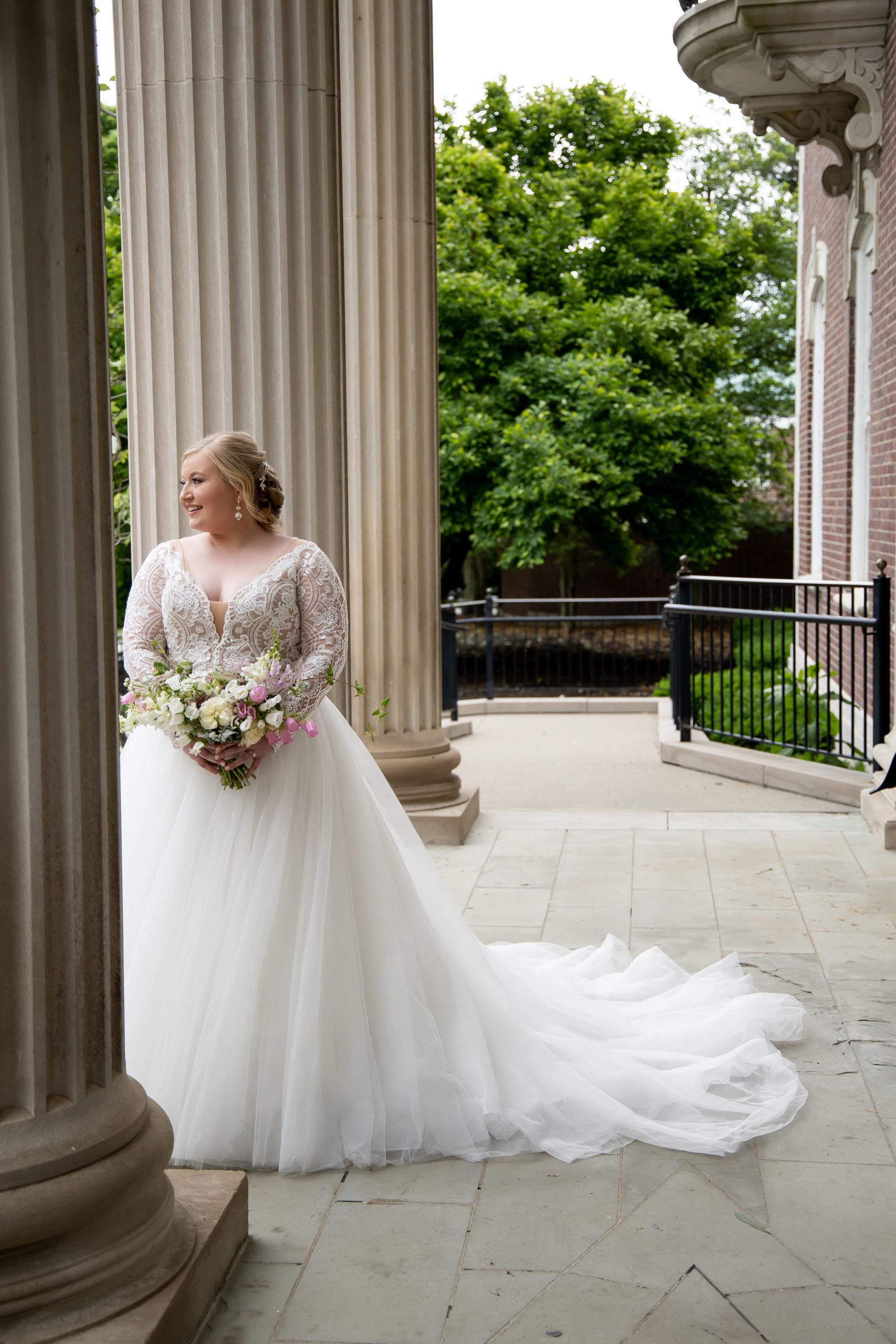 Mariée portant des robes de mariée Londres appelée Mallory Dawn par Maggie Sottero devant des piliers avec Groom
