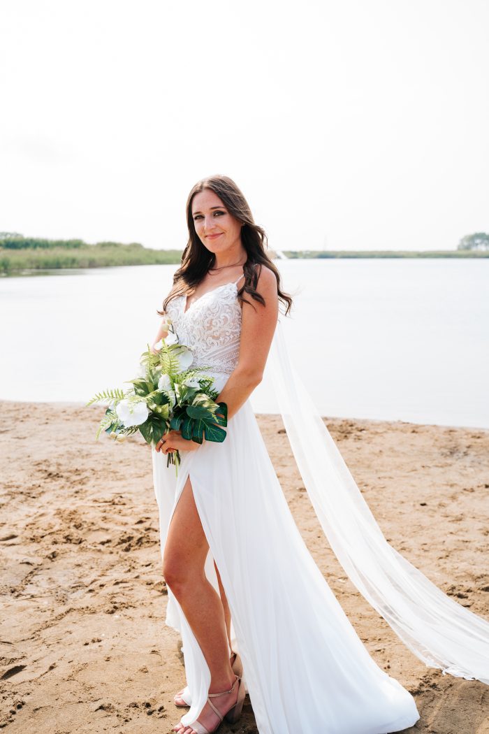 Bride Holding Bouquet on a Beach Wearing a Thigh-High Slit Sheath Wedding Dress Lorraine by Rebecca Ingram