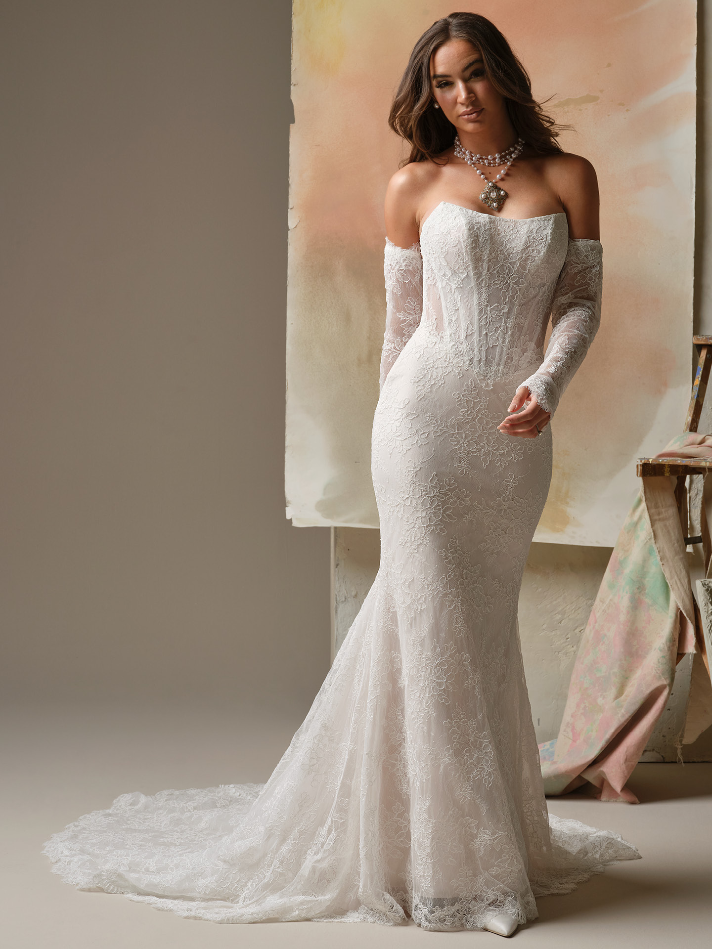 Maggie Sottero Ariadne sheath wedding dress featuring romantic allover lace, an off-the-shoulder neckline, and fitted silhouette for a timeless, feminine bridal look
