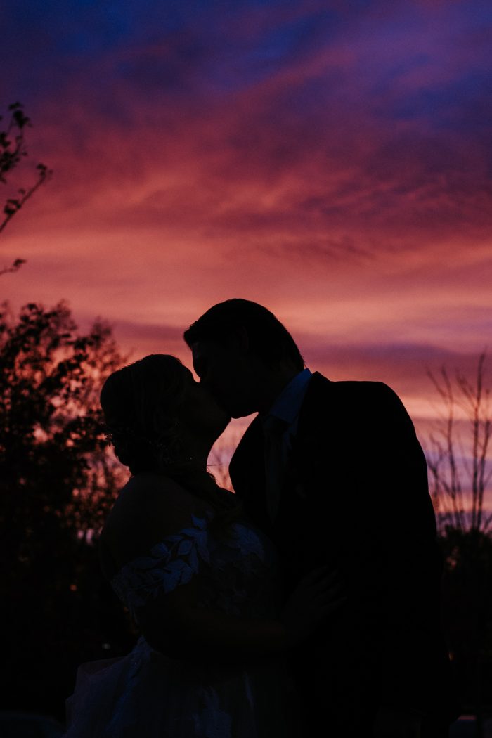 Bride And Groom Kissing Against Sunset