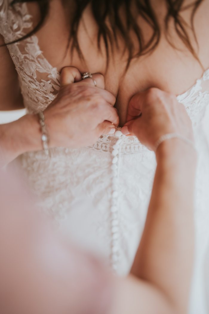 Bride wearing Betty by Rebecca Ingram and getting zipped up while she focuses on mental wellness tips