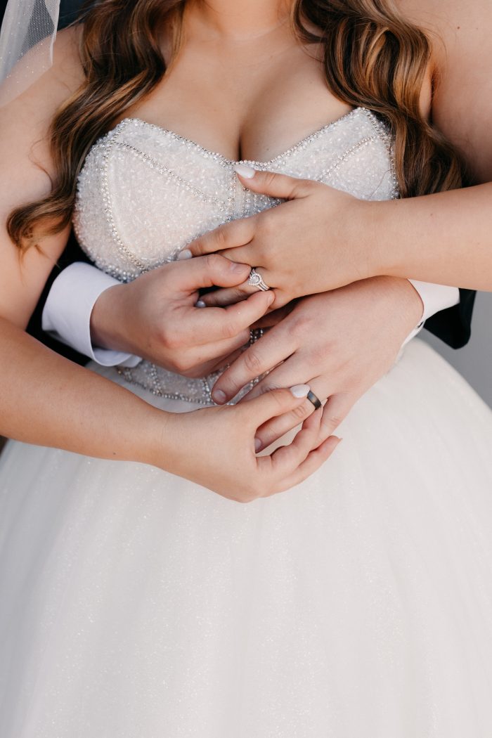 Bride wearing Elton by Sottero and Midgley and groom exchanging rings while focusing on wellness tips