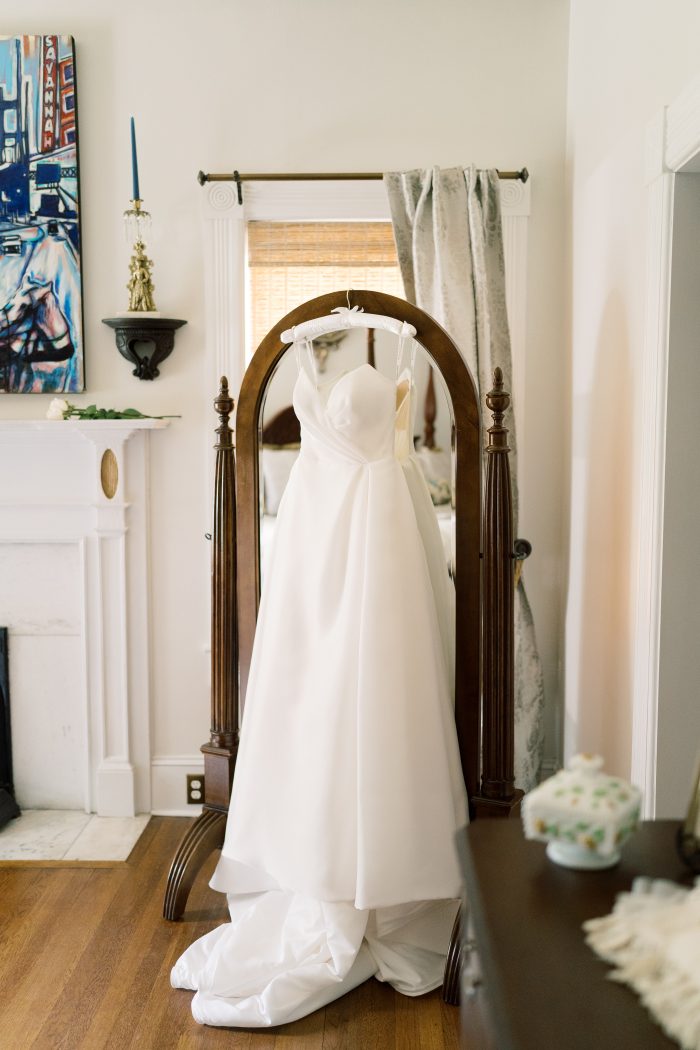 Nisha by Maggie Sottero hanging over a mirror