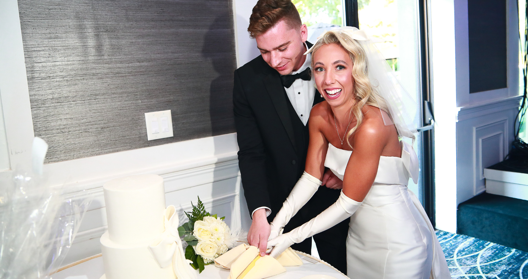 Blonde Bride In 90s Wedding Dress Called Mitchell By Maggie Sottero With Pearls, Groom, And Wedding Cake