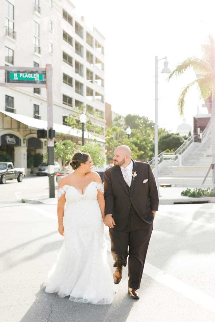 Plus Size Bride Holding Hands with Groom In the City Wearing Frederique Wedding Dress by Maggie Sottero