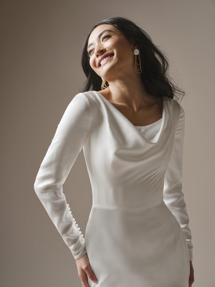 Close-up of an ivory wedding dress featuring a draped cowl neckline, long sleeves, and smooth satin fabric.