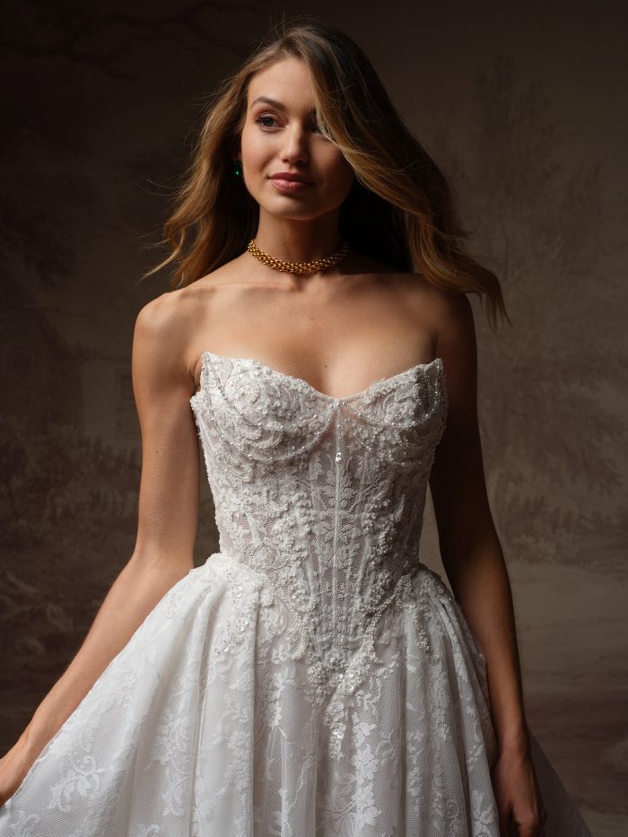 Close-up of the Maggie Sottero Ryland ballgown wedding dress featuring a strapless cat eye neckline, structured corset bodice, and intricate beaded lace.