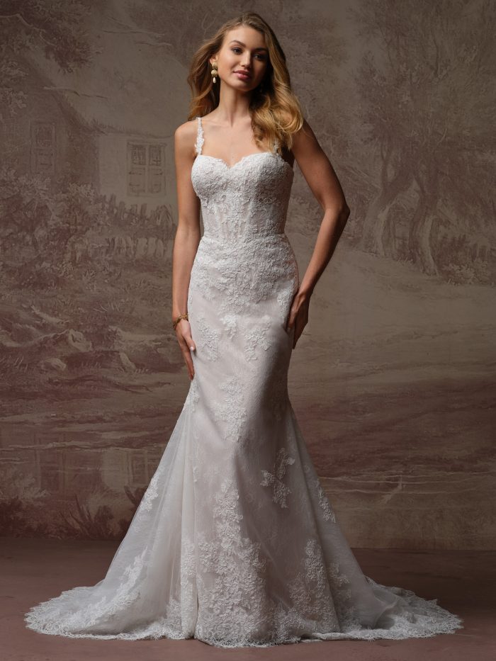 Bride wearing an ivory lace fit-and-flare wedding dress with a sweetheart neckline, delicate straps, fitted bodice, and soft train.