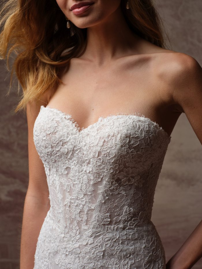 Close-up of an ivory lace wedding dress featuring a strapless sweetheart neckline, corset-style bodice, and delicate floral lace.
