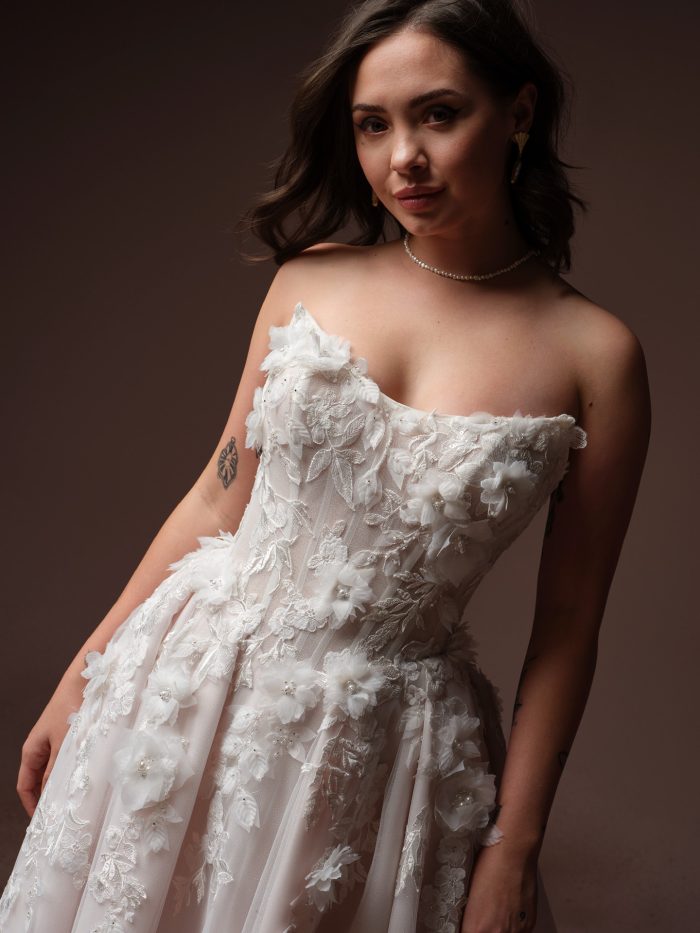 Close-up of the Rebecca Ingram Fleur wedding dress featuring a strapless cat eye neckline, structured corset bodice, and dimensional floral lace appliqués.