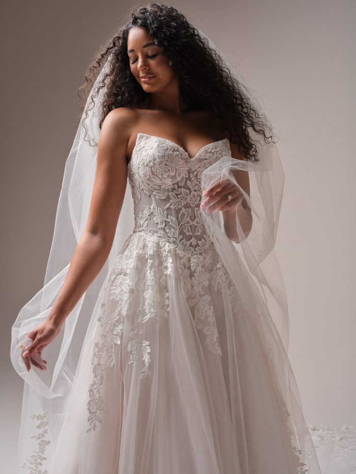 Bride wearing floral lace A-line wedding dress with sweetheart neckline and detachable veil, featuring layered tulle skirt with embroidered lace appliqués