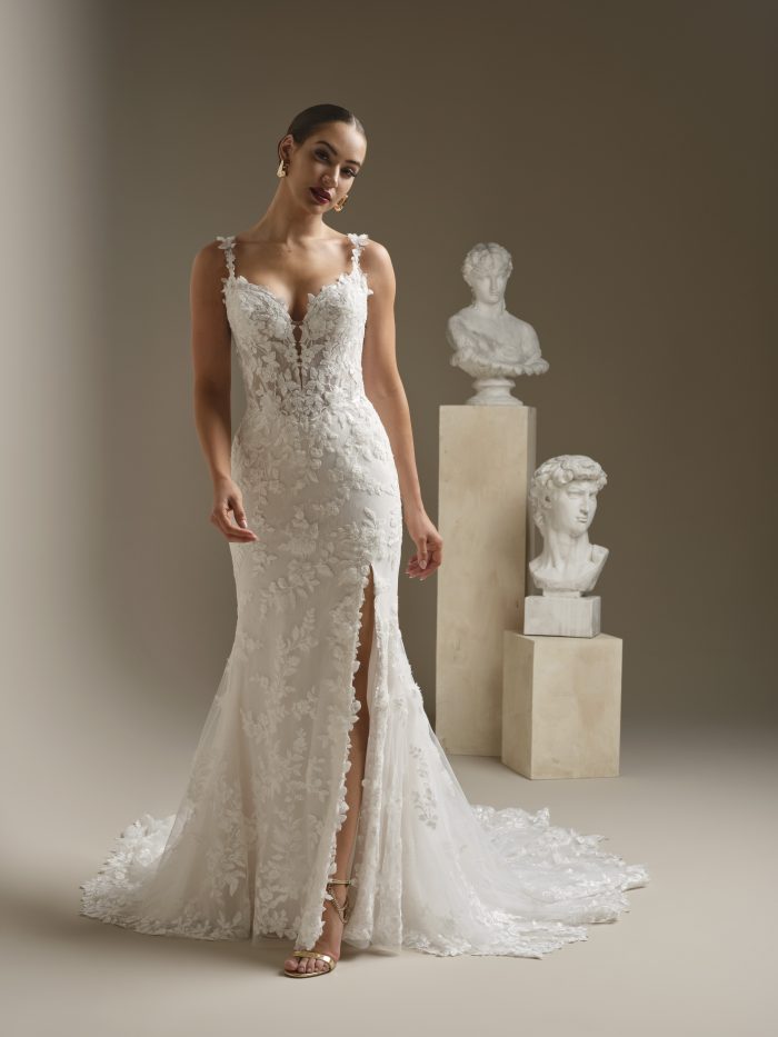 Bride wearing an ivory lace fit-and-flare wedding dress with a plunging sweetheart neckline, floral lace straps, front slit, and sweeping train.