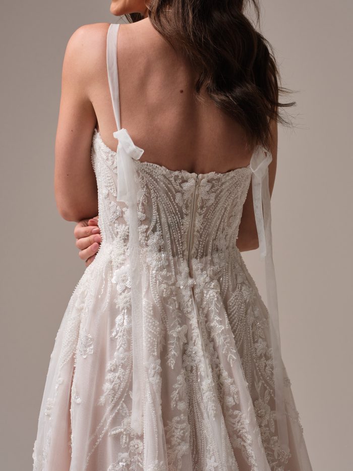 Back view of the Rebecca Ingram Angie wedding dress featuring an illusion lace bodice with beaded and sequined details and attached tulle self-tie straps.