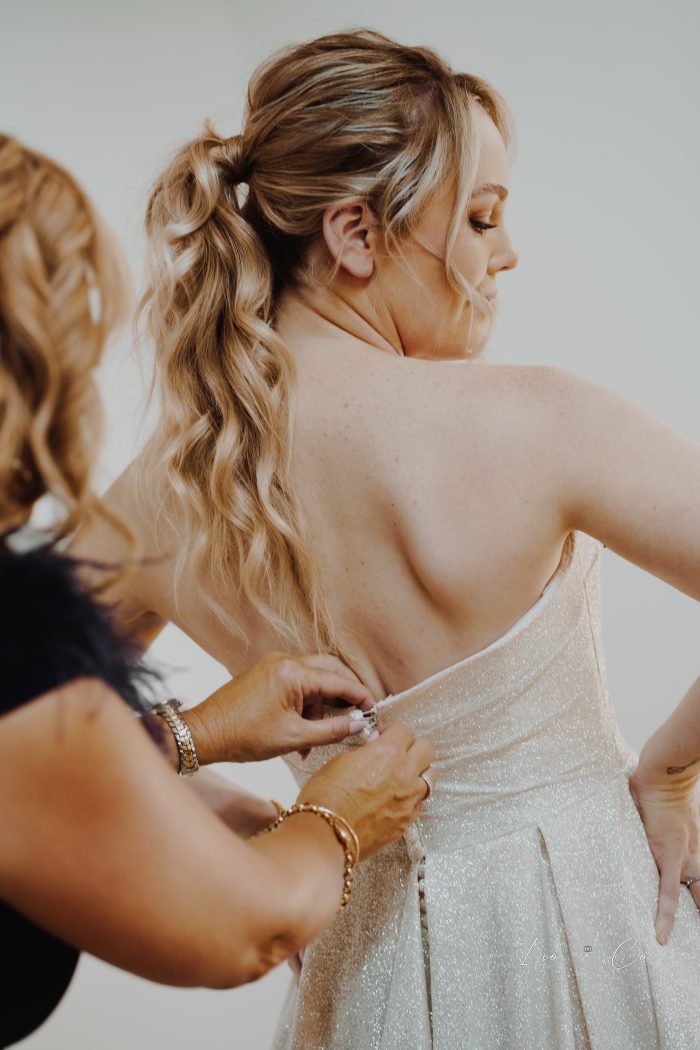 Bride's Friend Buttoning Up Wedding Dress