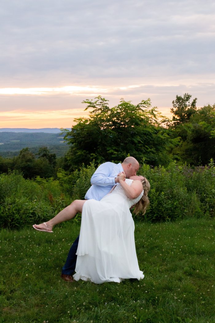 Groom Dipping and Kissing Bride in Meadow