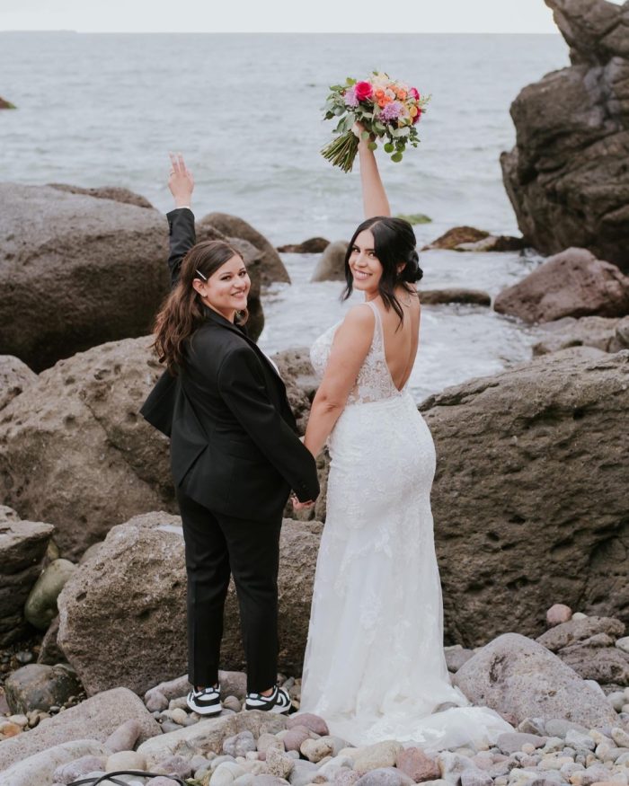 Bride wearing sneakers as practical wedding shoes with wife in Greenley wedding dress by Maggie Sottero
