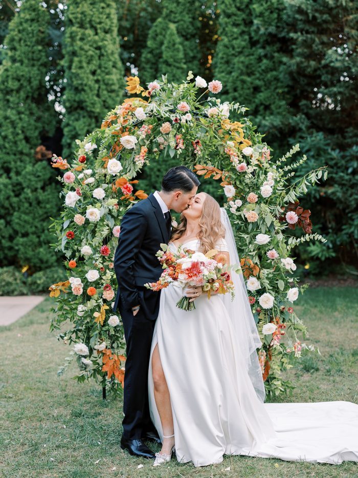 Bride wearing Ekaterina wedding gown by Maggie Sottero in front of a floral arch inspired by the Pantone Color of the Year 2024.