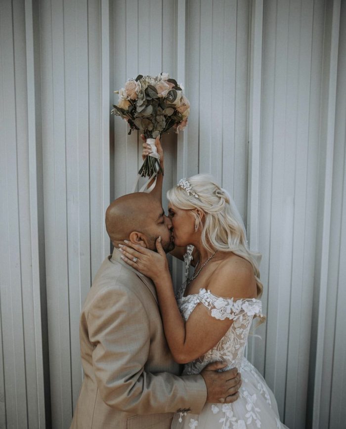 Bride wearing Harlem wedding dress by Maggie Sottero kissing her husband 