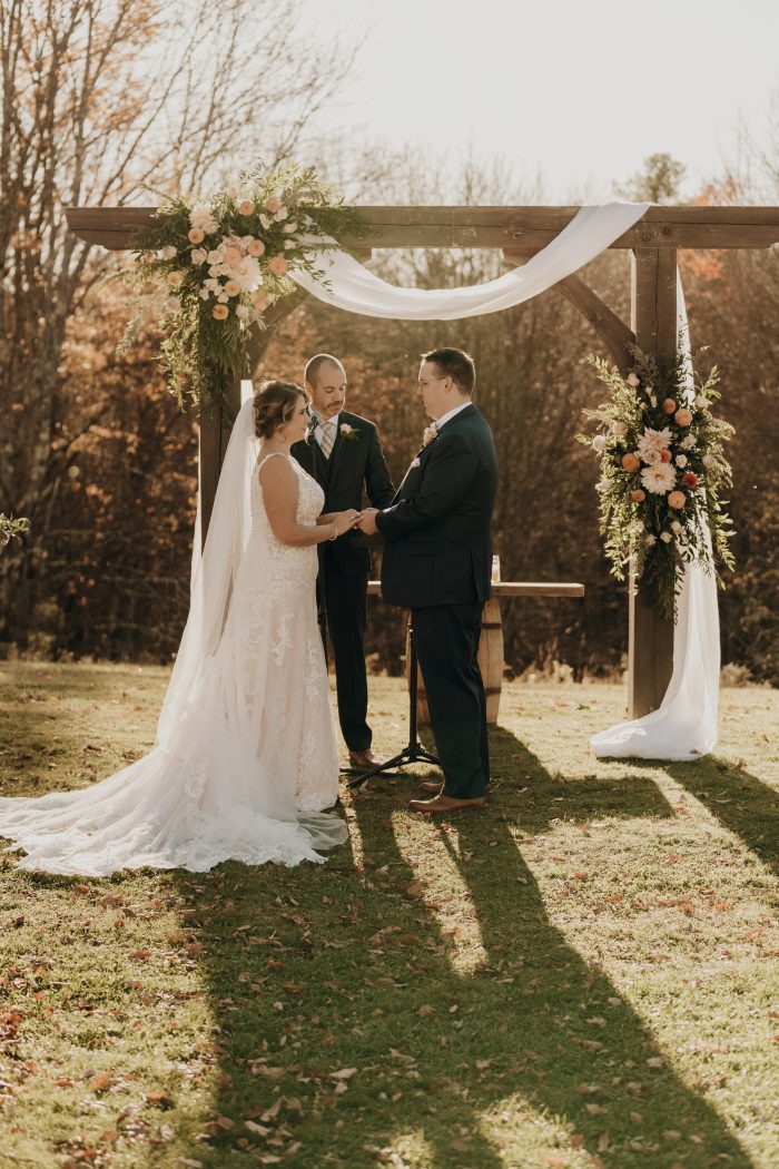 Bride wearing Johanna wedding dress by Maggie Sottero with her husband under the arch.