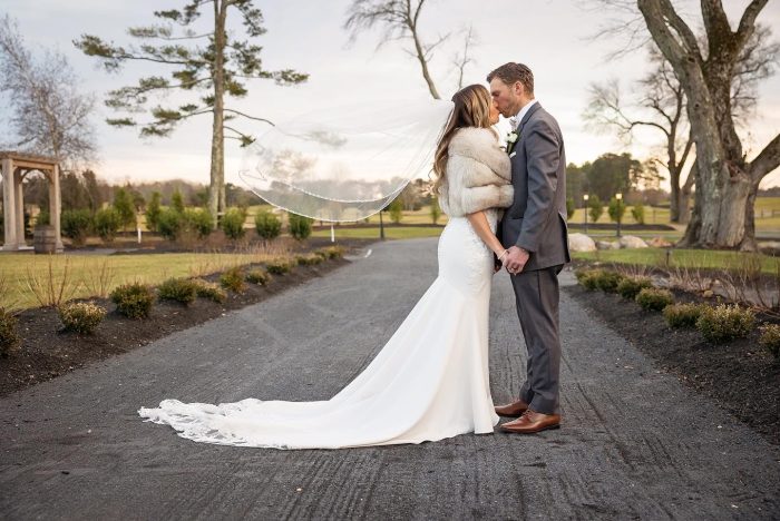 Bride wearing Nikki crepe fabric wedding dress by Maggie Sottero and kissing her husband