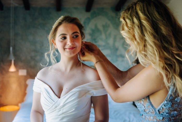 Bride wearing a bridesmaid's earrings as her something borrowed wedding tradition