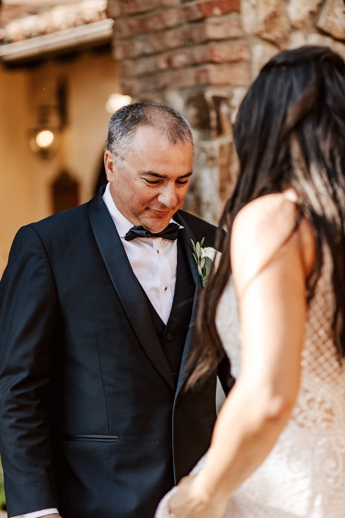 Father looking at his daughter before walking her down the aisle as a wedding tradition