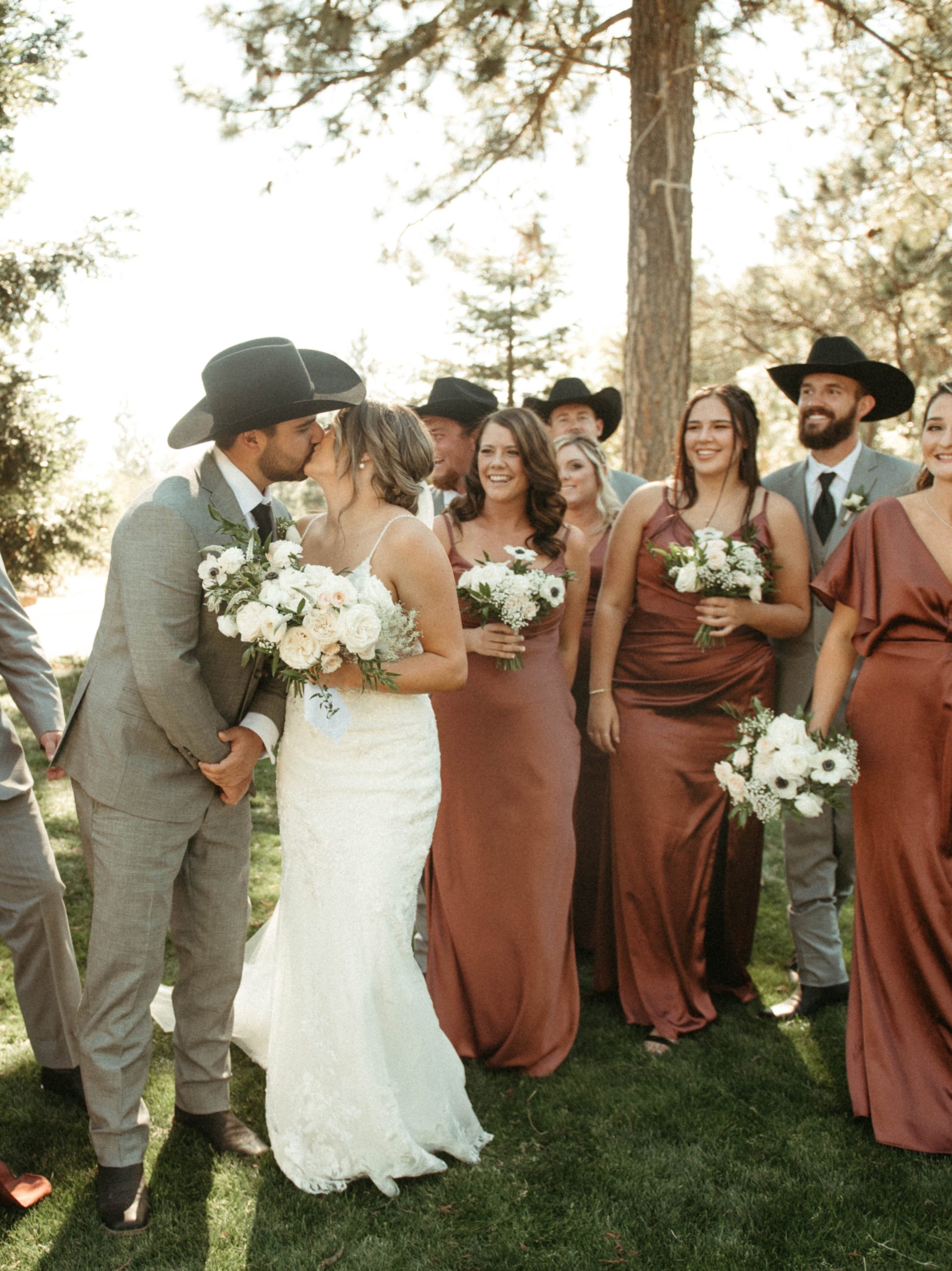 Bride wearing Fontaine by Maggie Sottero kisses her husband in front of bridesmaids and groomsmen