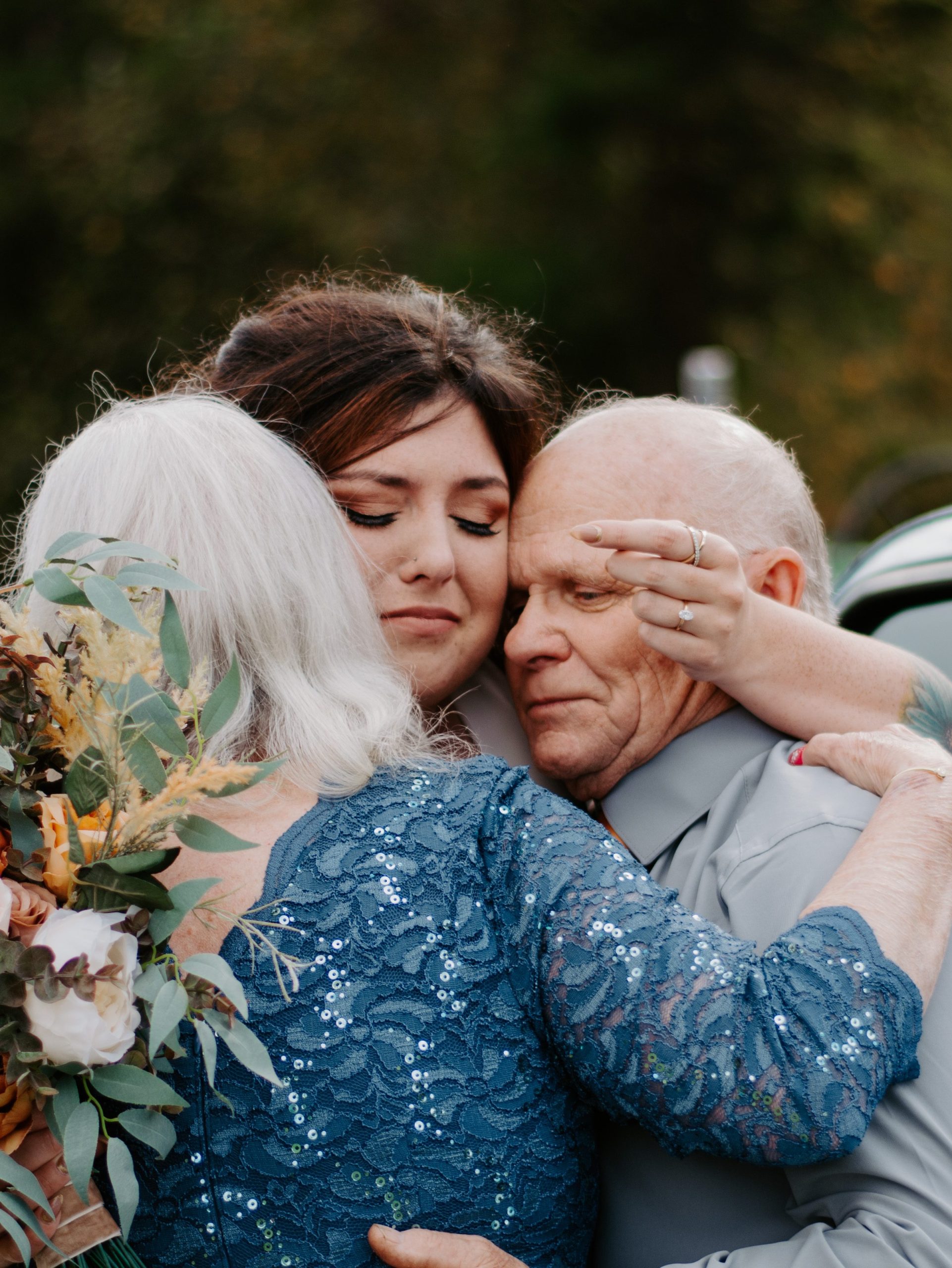 Bride with her mother and father hugging in new wedding tradition