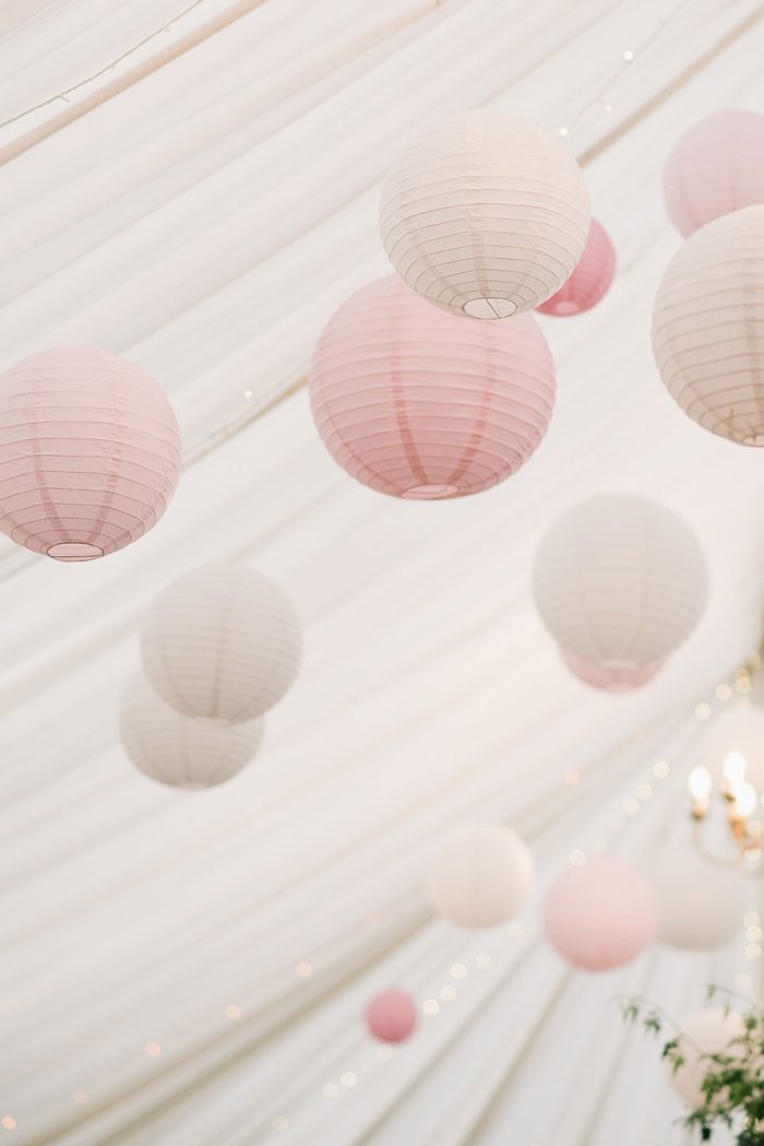Hanging pink and white lanterns in a reception tent