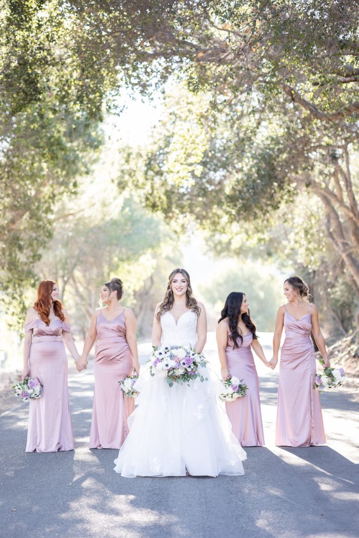 Bride wearing Lettie wedding dress by Rebecca Ingram with bridesmaids in spring wedding colors