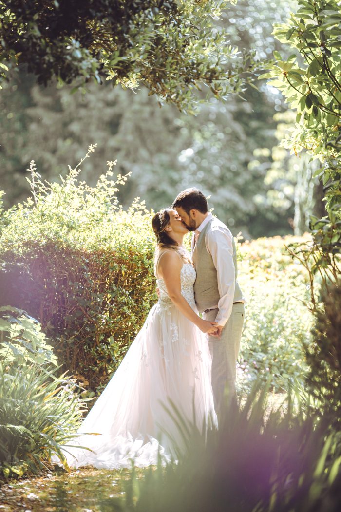 Bride wearing Marisol wedding dress by Rebecca Ingram kissing her husband during their garden party wedding