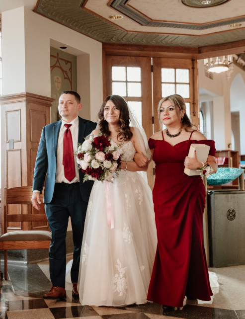 Michelle walking down the aisle with her father and the mother of the bride in Kalina by Rebecca Ingram