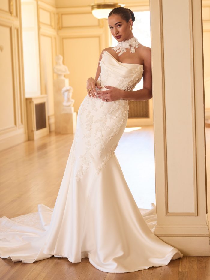 Model wearing the Burke fit and flare wedding dress, featuring a draped satin strapless neckline, floral lace appliqués throughout the bodice and skirt, and a matching high-neck lace accessory for a dramatic, modern bridal look.