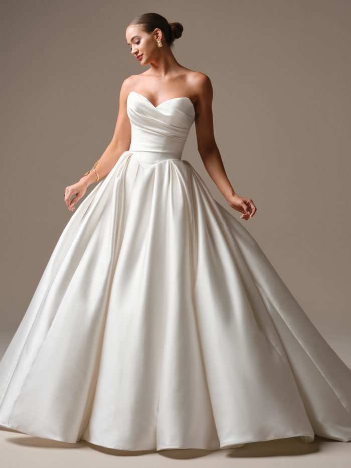 Model wearing the Elias ball gown wedding dress, featuring a ruched satin sweetheart bodice and a full, voluminous skirt with elegant pleating for a timeless, sculptural bridal silhouette.